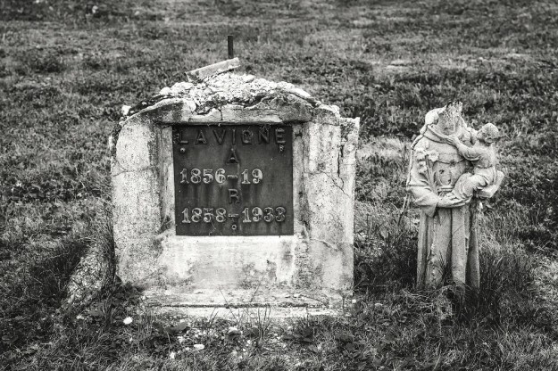 On old cemetery headstone next to a headless statue.